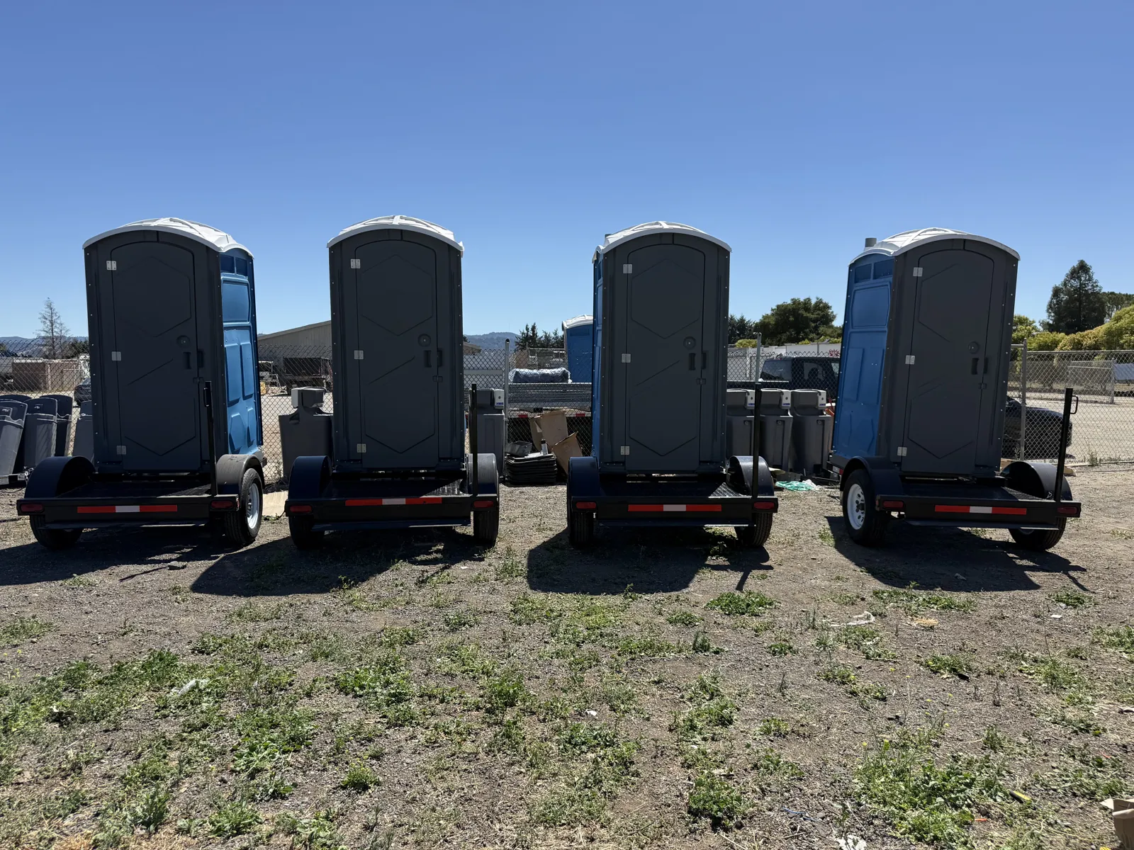 A row of clean Pro Portable Restrooms units staged in the yard, ready for delivery