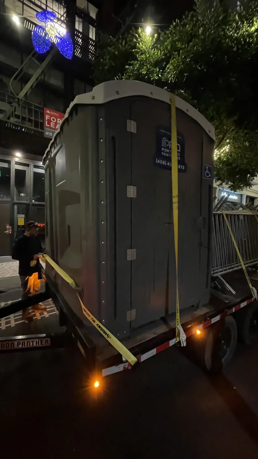 A large Pro Portable Restrooms unit delivered downtown at night