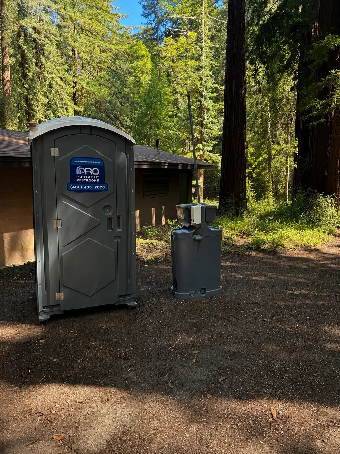 A Pro Portable Restrooms unit and waste bin at a redwood park site
