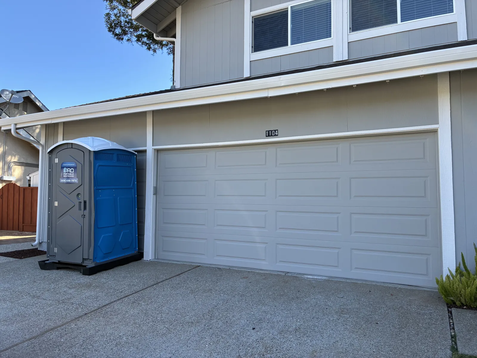A clean Pro Portable Restrooms unit placed at a residential property driveway