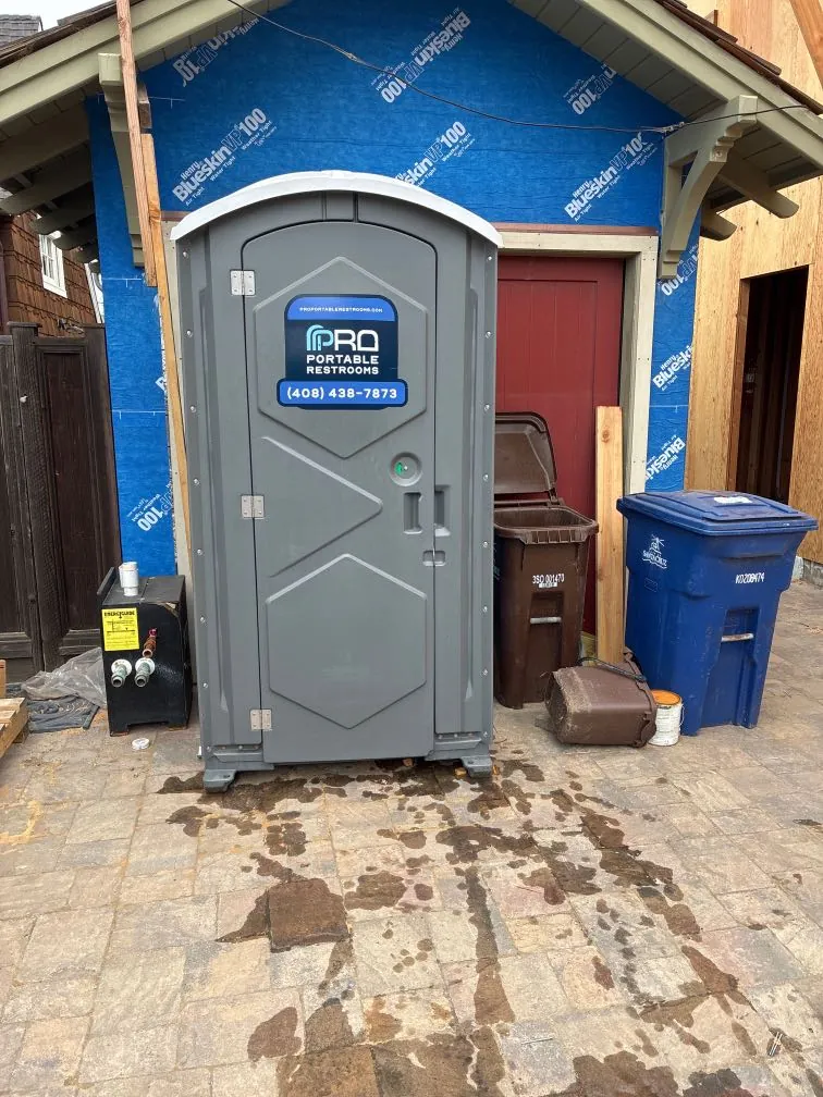A Pro Portable Restrooms unit on site at a home remodel wrapped in building wrap