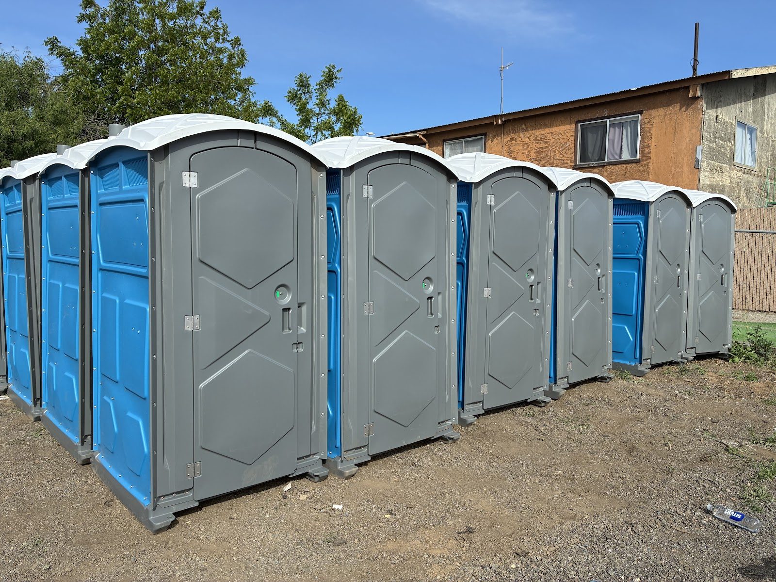 A row of clean Pro Portable Restrooms porta potties lined up and ready for delivery