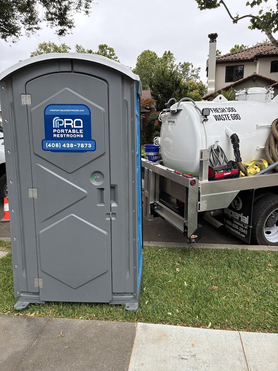 A porta potty delivered alongside a freshwater holding tank at a residential site